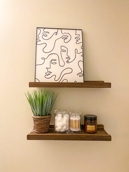 Wall art deco with floating shelves and small plant. I also added two clear containers to keep things clean and hold cotton balls and qtips. in addition I put a wonderful smelling candle